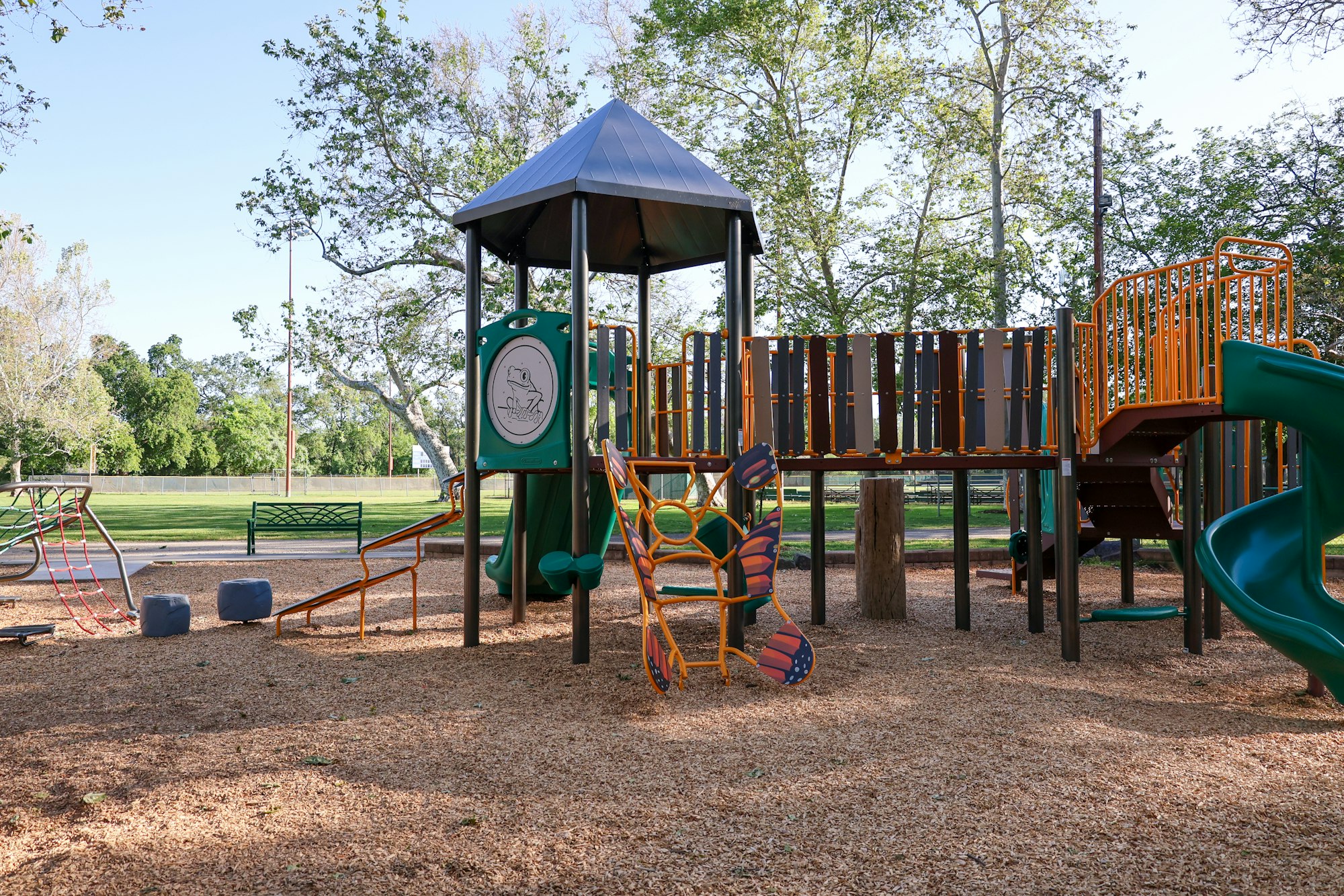 Playground with slide, swings, and climbing structures on a sunny day.