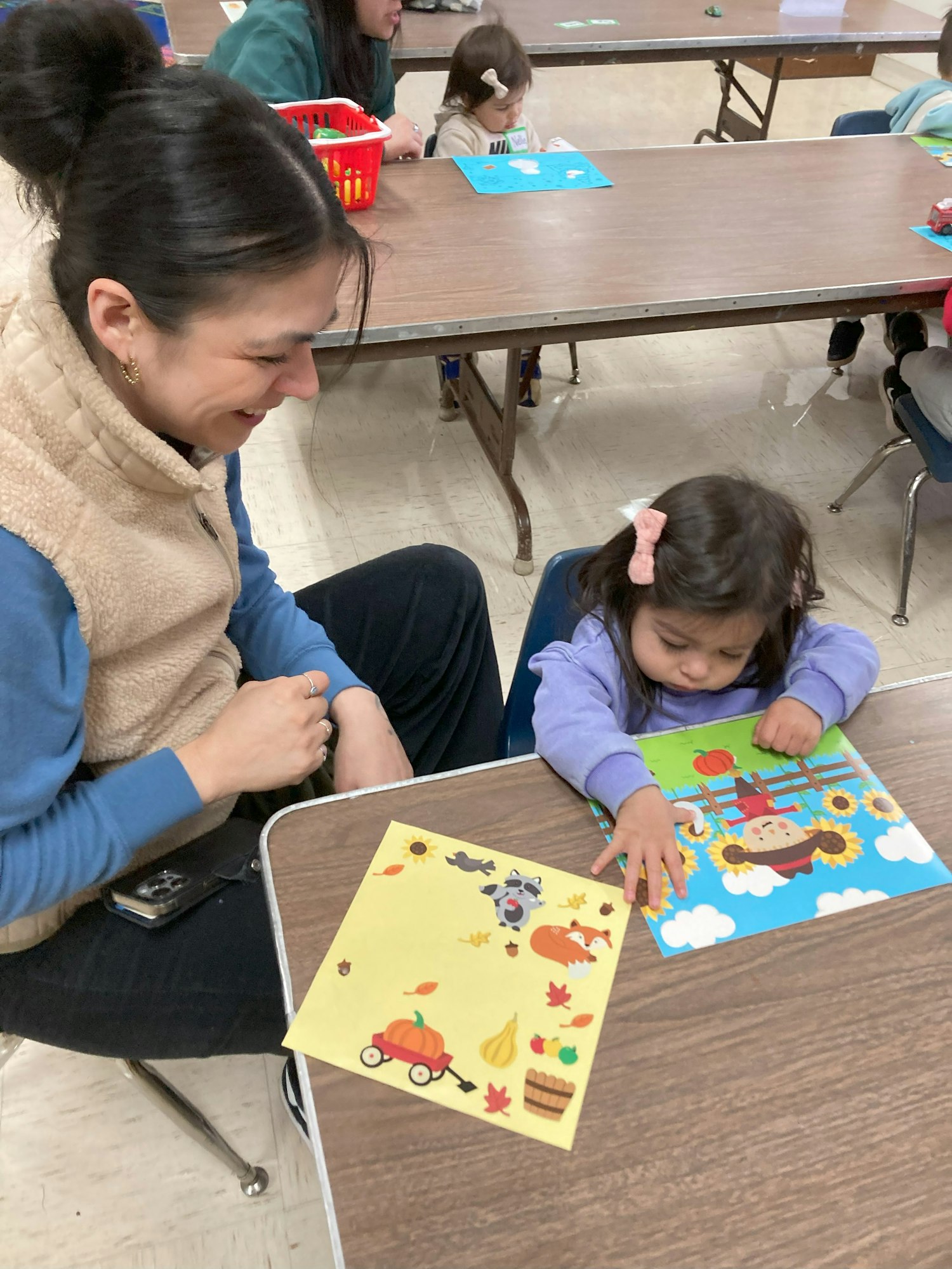 A woman and a child do a craft activity with colorful papers at a table.