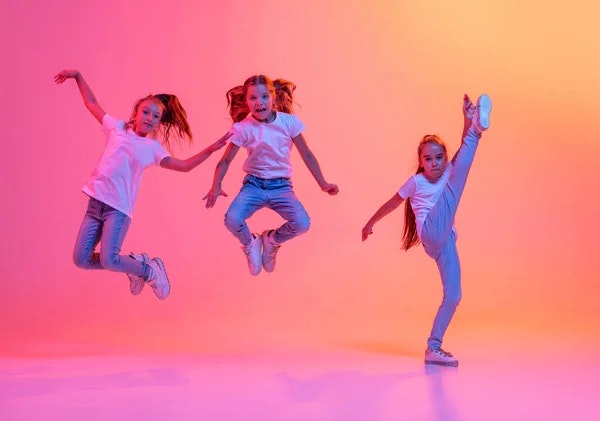 Three kids jumping against a pink and orange gradient background.