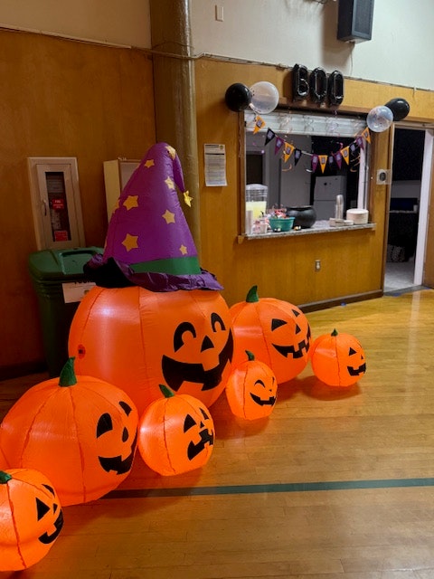 Inflatable Halloween pumpkins, including a large one with a witch's hat, arranged in a festive indoor setting.