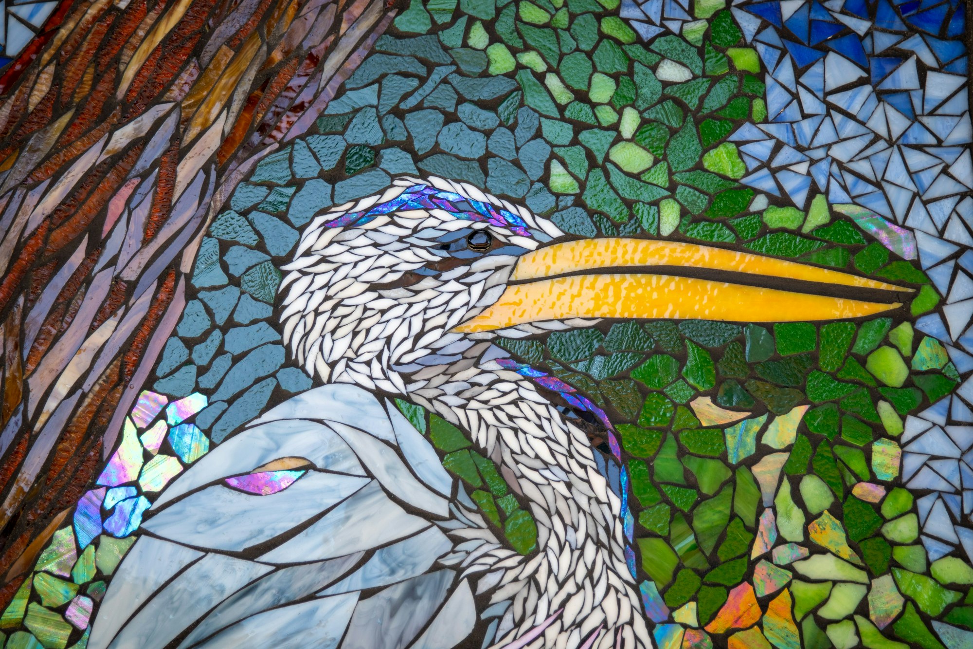 Colorful mosaic artwork depicting a bird with a tree and leaves in the background.