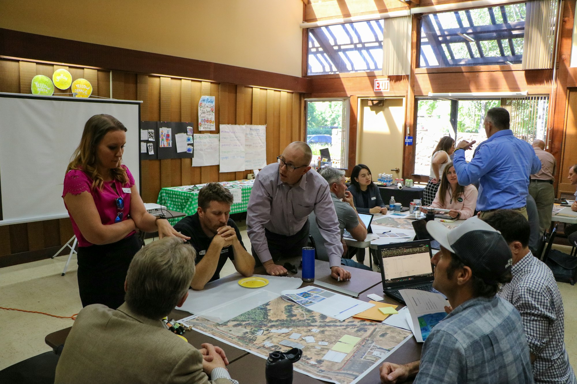 People gathered around a table with documents, seeming engaged in a discussion or workshop.