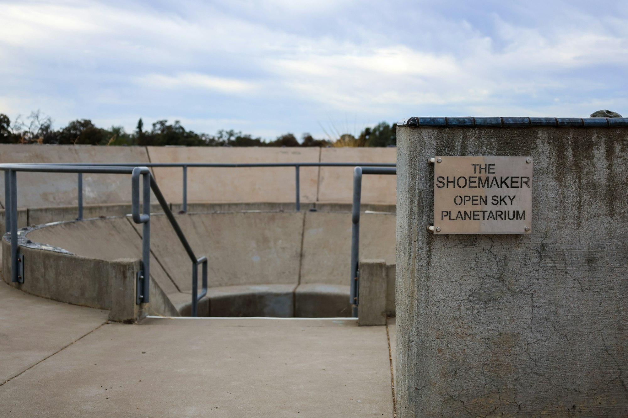 Concrete structure with a sign saying "The Shoemaker Open Sky Planetarium" and a circular staircase.