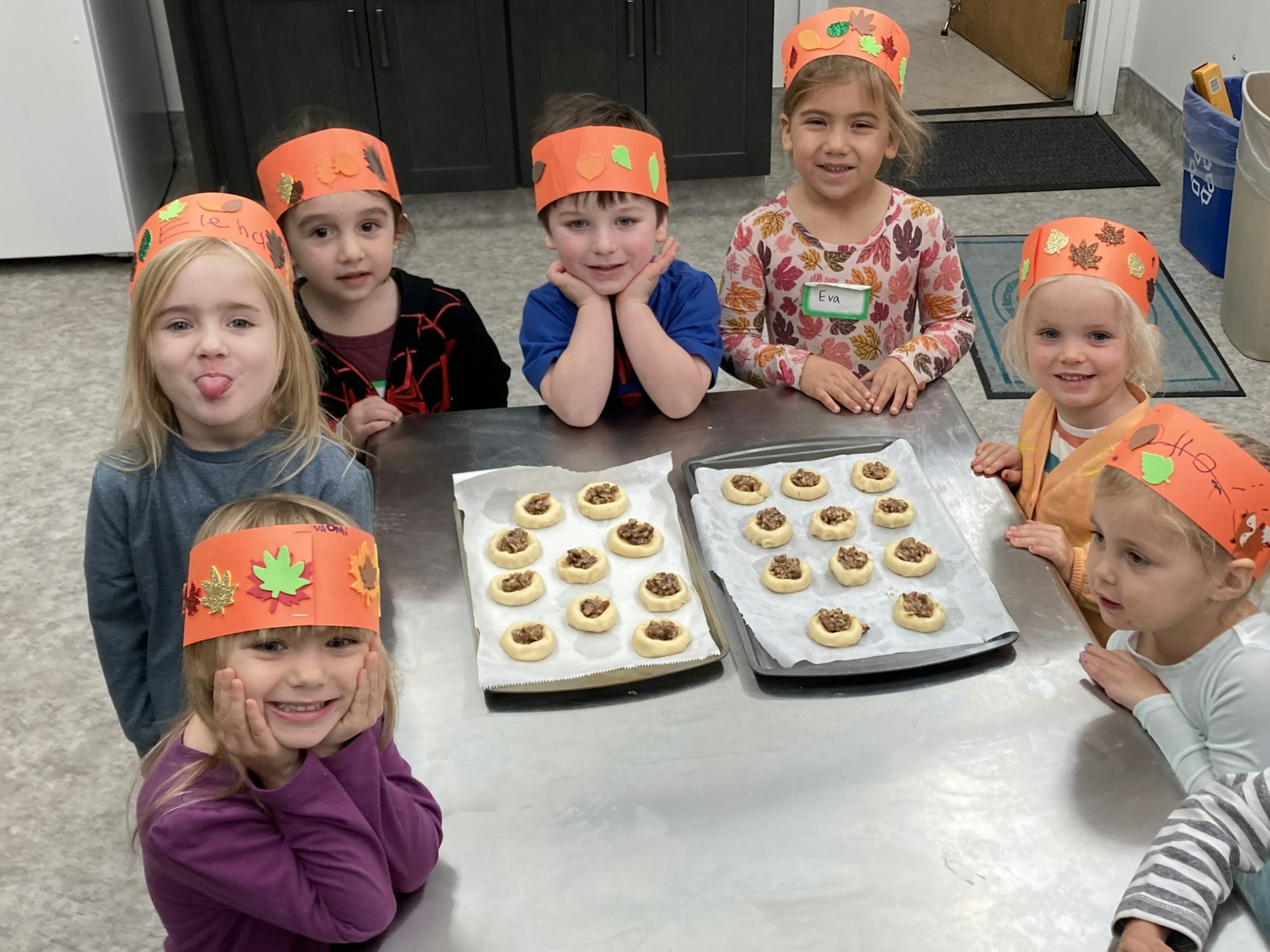 A group of children wearing festive hats smiles around a table with freshly baked cookies. Fun and creativity abound!
