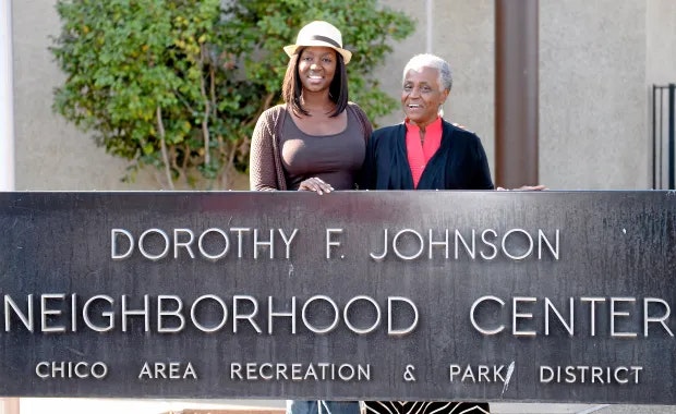 Two people stand smiling behind the Dorothy F. Johnson Neighborhood Center sign.