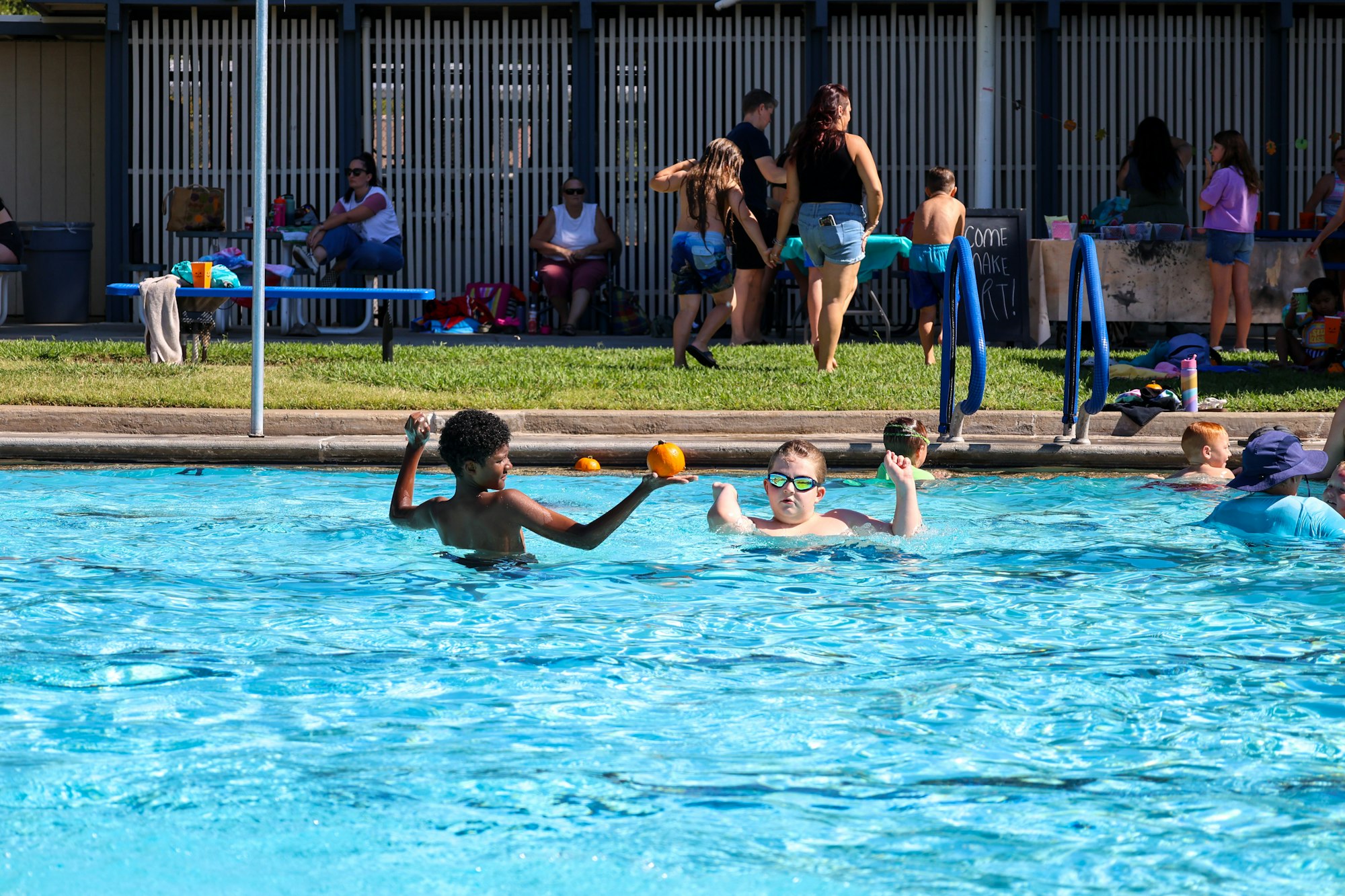 May contain: leisure activities, person, sport, swimming, water, water sports, summer, clothing, shorts, pool, swimming pool, accessories, glasses, bag, handbag, swimwear, footwear, shoe, hat, bench, furniture, ball, basketball, and basketball (ball)