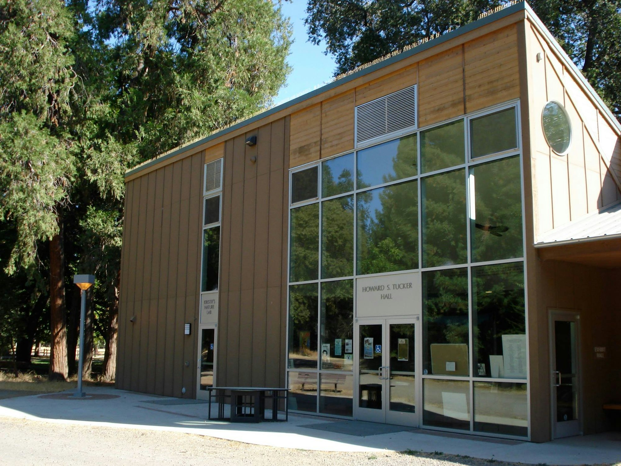 A modern building with large windows, labeled "Howard S. Tucker Hall," surrounded by trees.