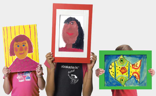 Three children are holding up colorful framed artworks: two portraits and one vibrant fish painting.