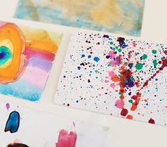 The image features colorful, abstract watercolor art on paper, showcasing vibrant splashes and patterns.