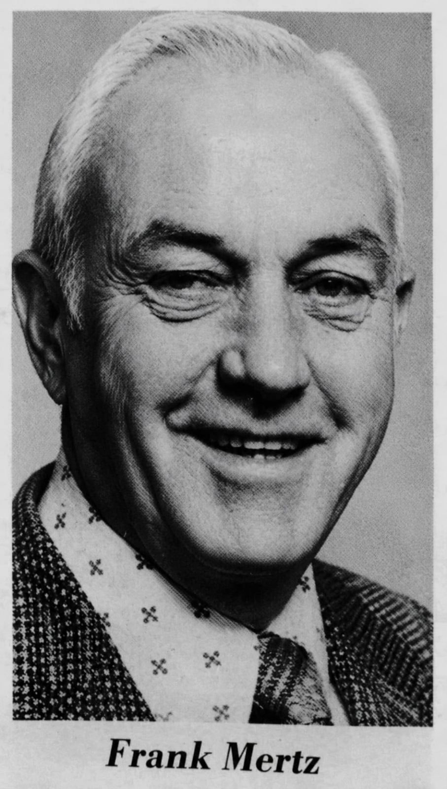 The image features a black-and-white portrait of a smiling man named Frank Mertz, wearing a patterned shirt and a suit.