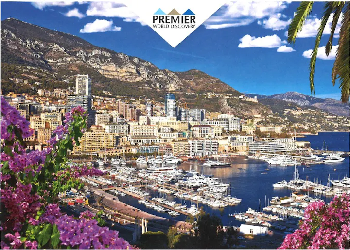 A scenic view of Monaco featuring luxury yachts, vibrant flowers, and mountains under a blue sky, with a logo in the corner.