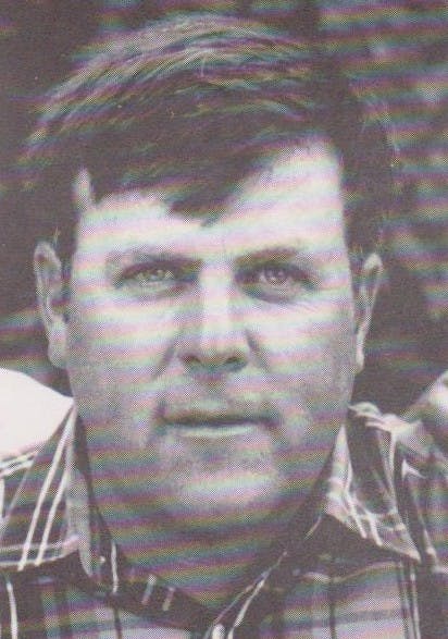 A black and white close-up portrait of a man wearing a plaid shirt.