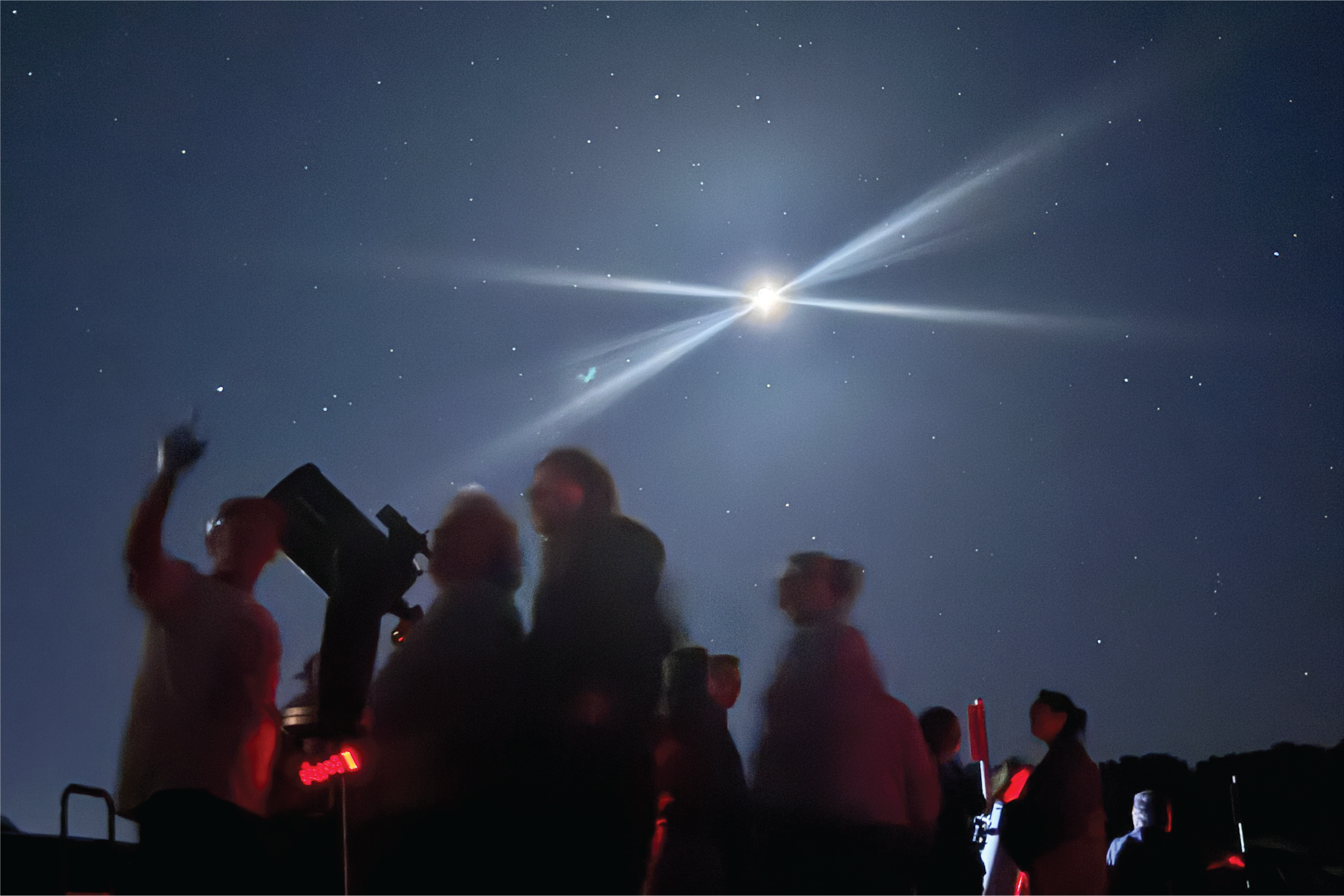 People stargazing with a telescope under a night sky lit up by a bright celestial body, possibly the moon or a planet.