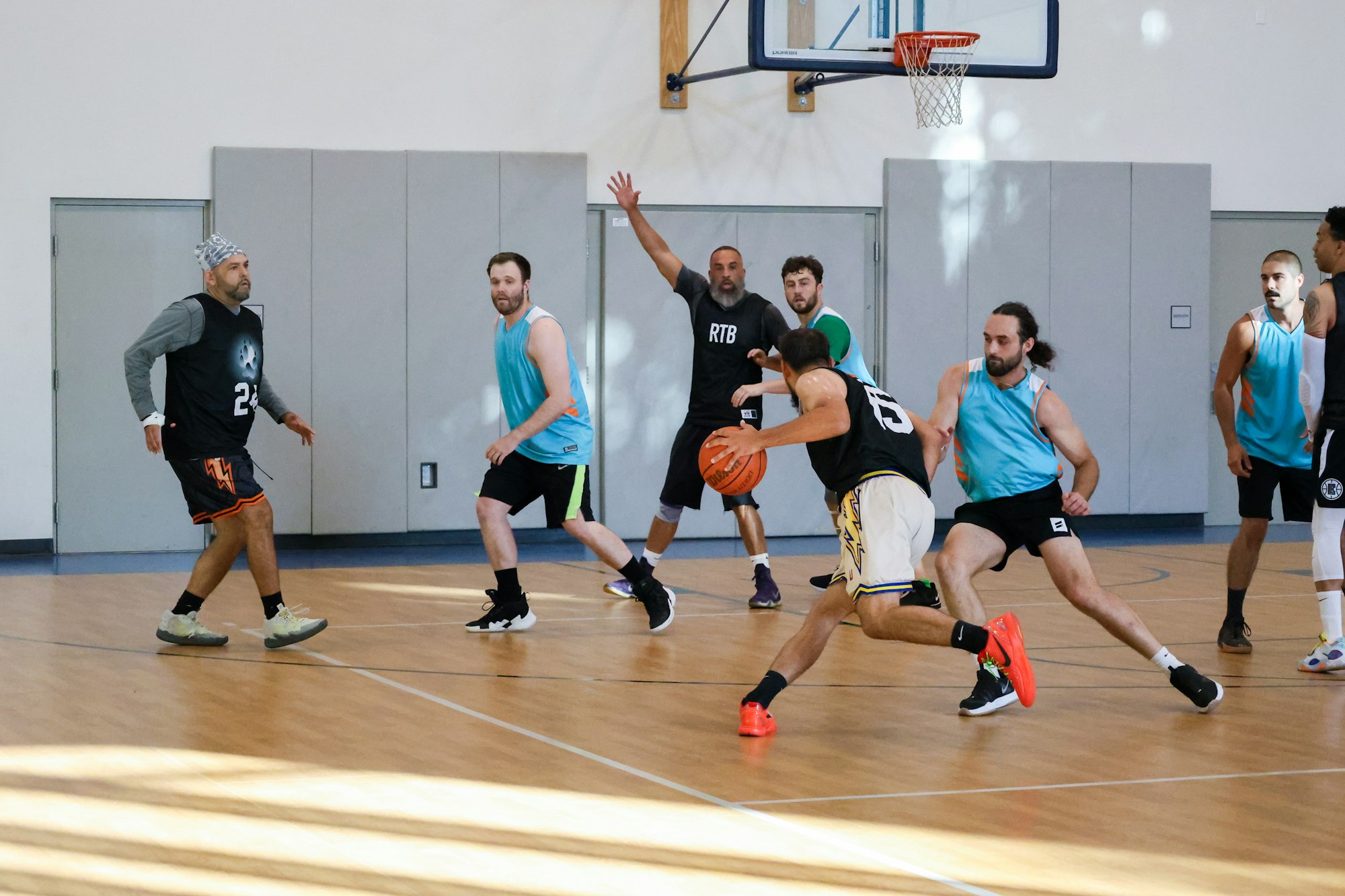 Men playing indoor basketball, man in foreground dribbling with defenders around.