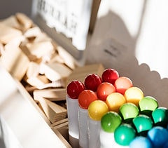 The image shows a collection of colorful wooden balls arranged in a row, alongside rectangular wooden pieces.