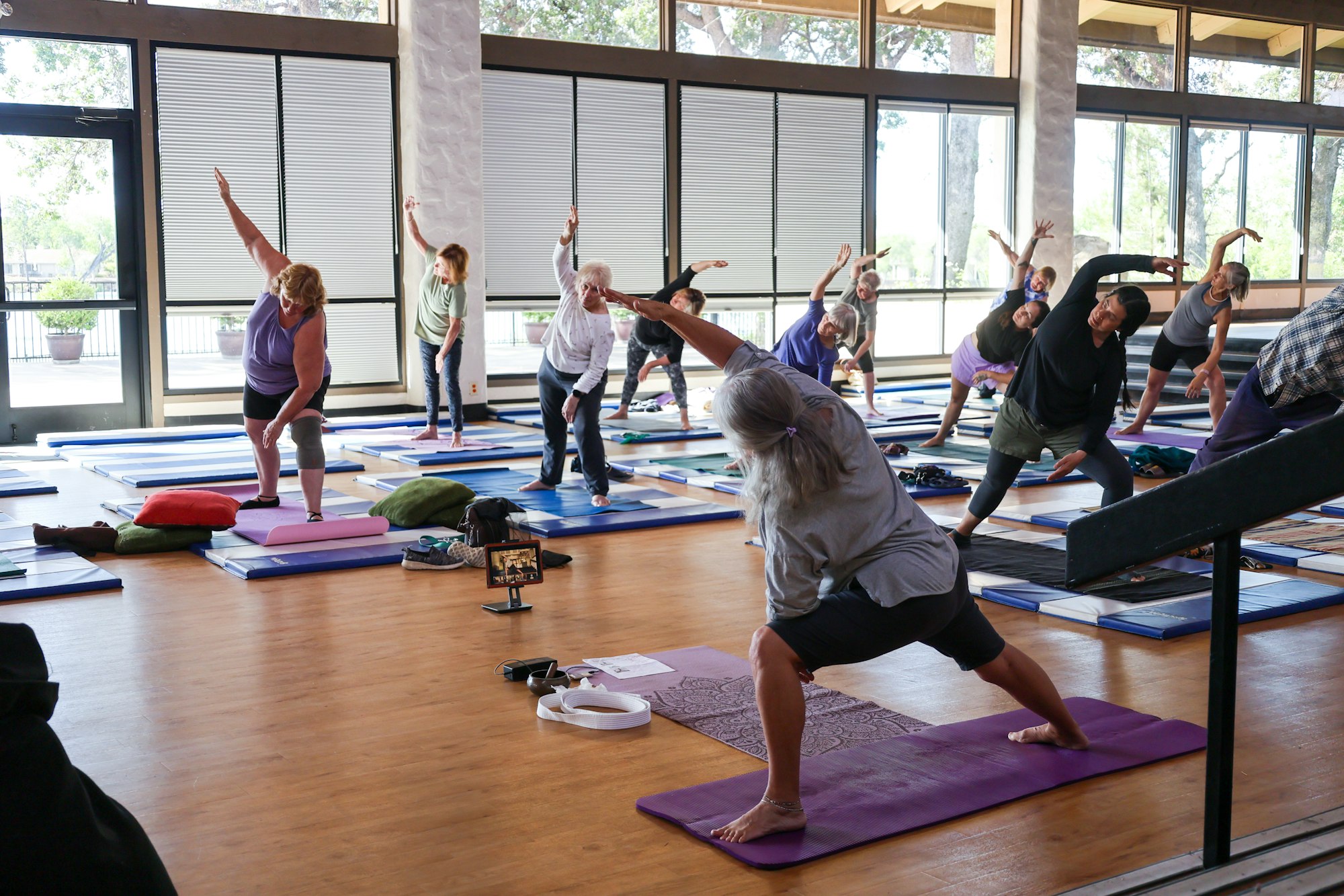 A group of people participating in a yoga class indoors, performing stretching exercises on mats.