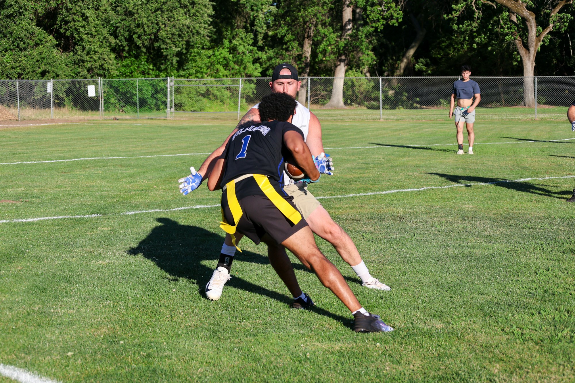 Two men playing football, one in black and blue outfit attempting to catch the ball while the other tries to block.