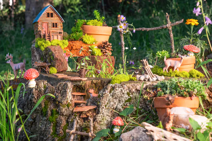 A whimsical miniature scene featuring a log cabin, tiny animals, plants, and colorful mushrooms on a tree stump.