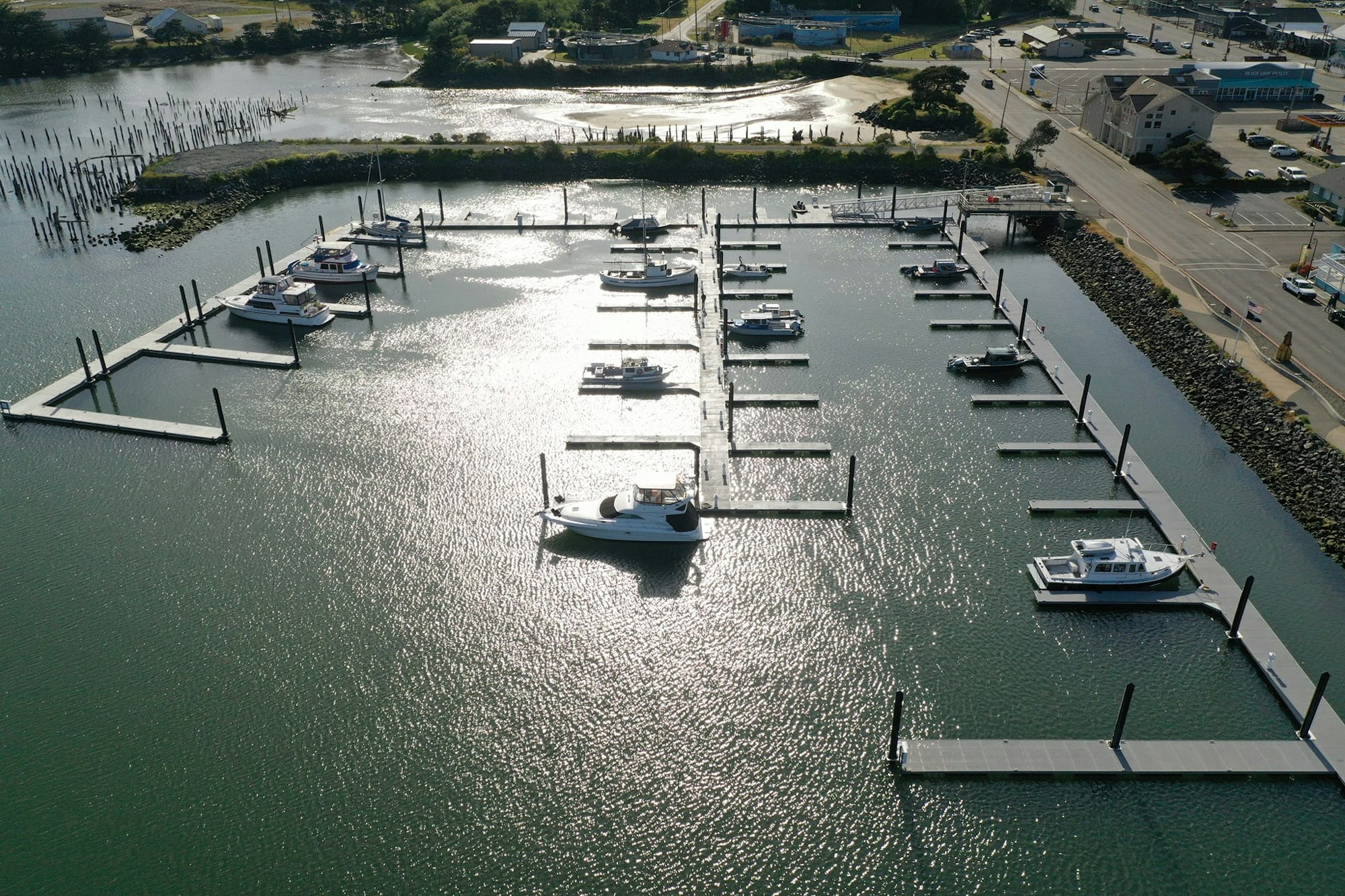 Aerial view of a marina with boats and adjacent road with vehicles.