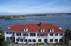 A large white building with a red roof sits by the water, surrounded by scenic views of the river and landscape.