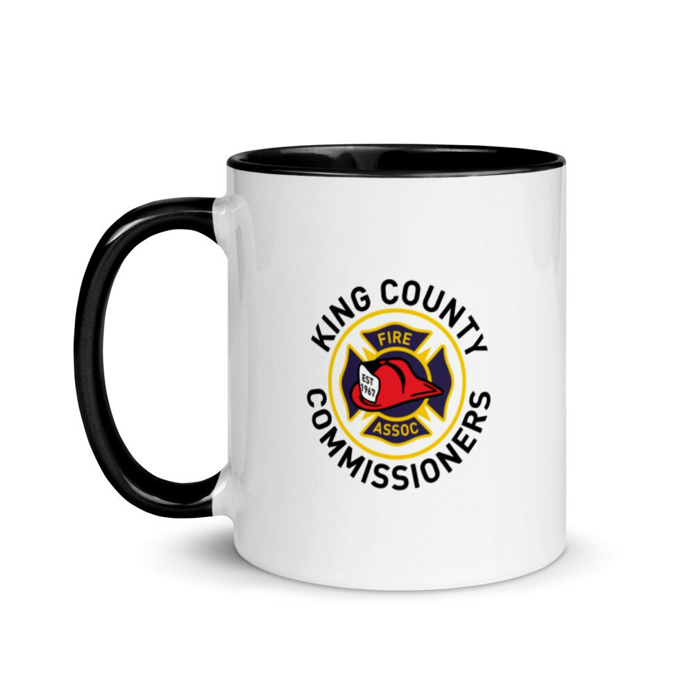 A coffee mug featuring the King County Fire Commissioners Association logo with a firefighter's helmet design.