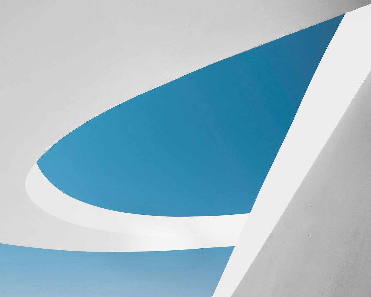 Abstract architectural design with curved white structures and clear blue sky.