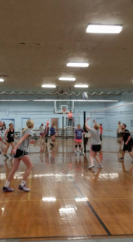 People playing indoor volleyball in a gymnasium.