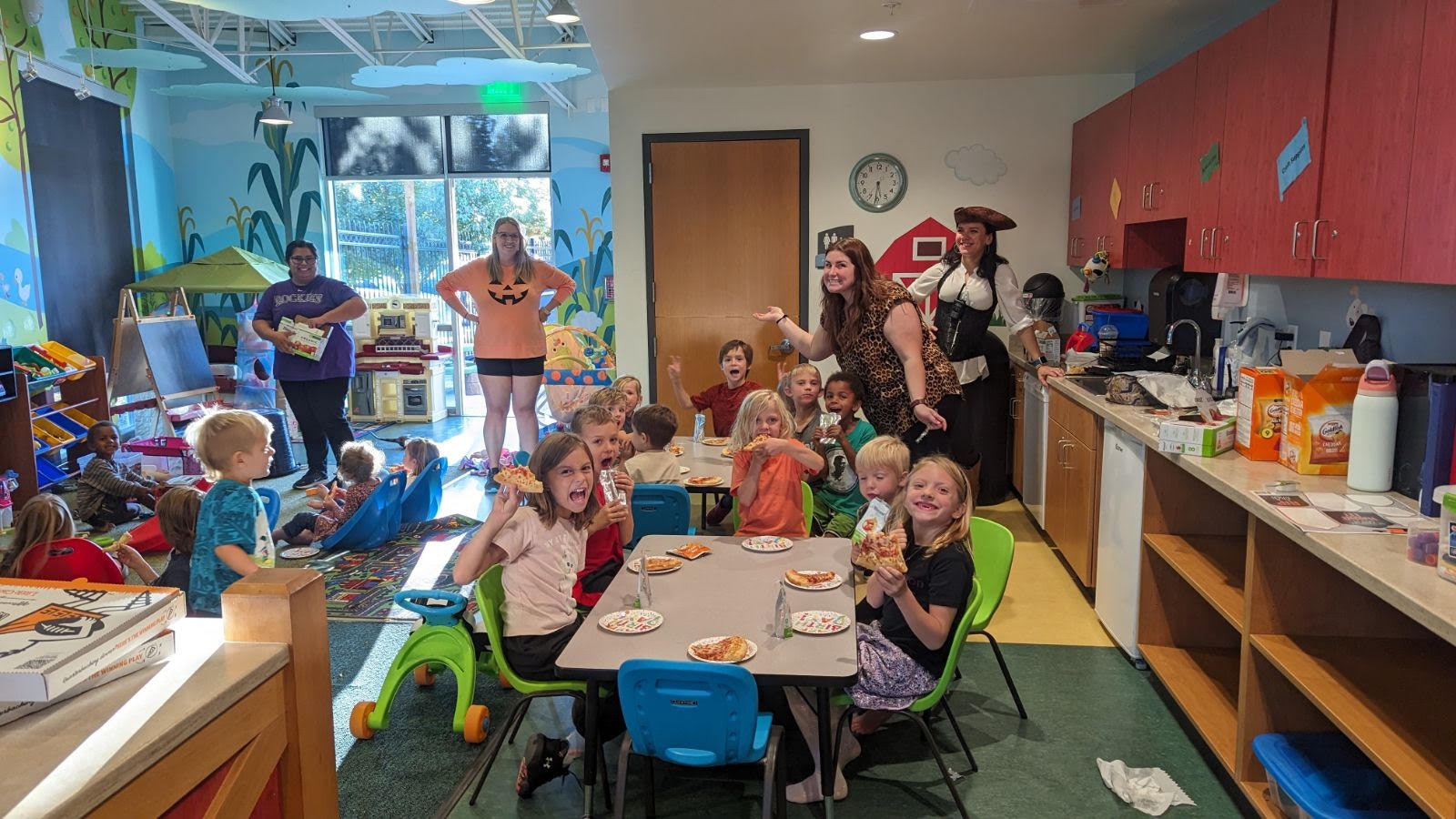 A lively classroom scene with children eating pizza, adults supervising, colorful decor, parents night out, child watch