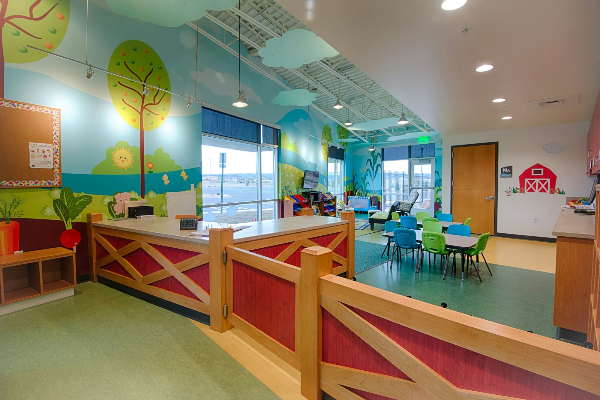 A colorful children's playroom with farm-themed decorations, a reception area, and seating for kids.