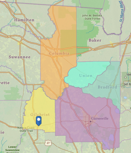 A map showing colored regions/counties, roads, place names like Columbia, Gainesville, a forest, and a pinpoint on Gilchrist.