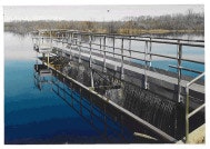 A water treatment or filtration structure in a body of water, featuring metal railings and a platform.