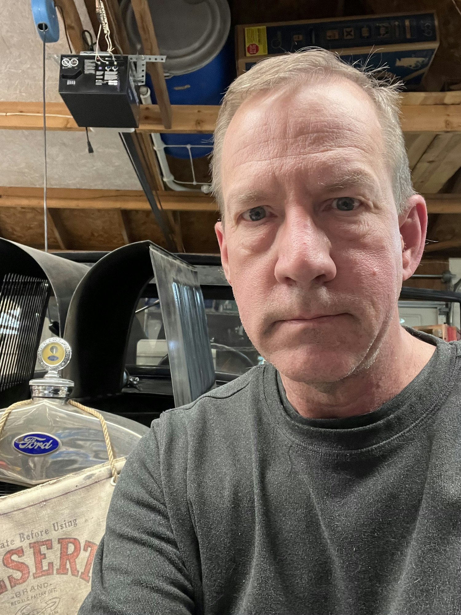 May contain: face, head, person, photography, portrait, plywood, wood, adult, male, man, shelf, clothing, and t-shirt