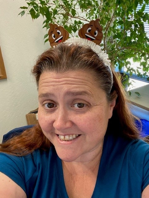 A smiling woman wearing a headband with two poop emoji decorations.