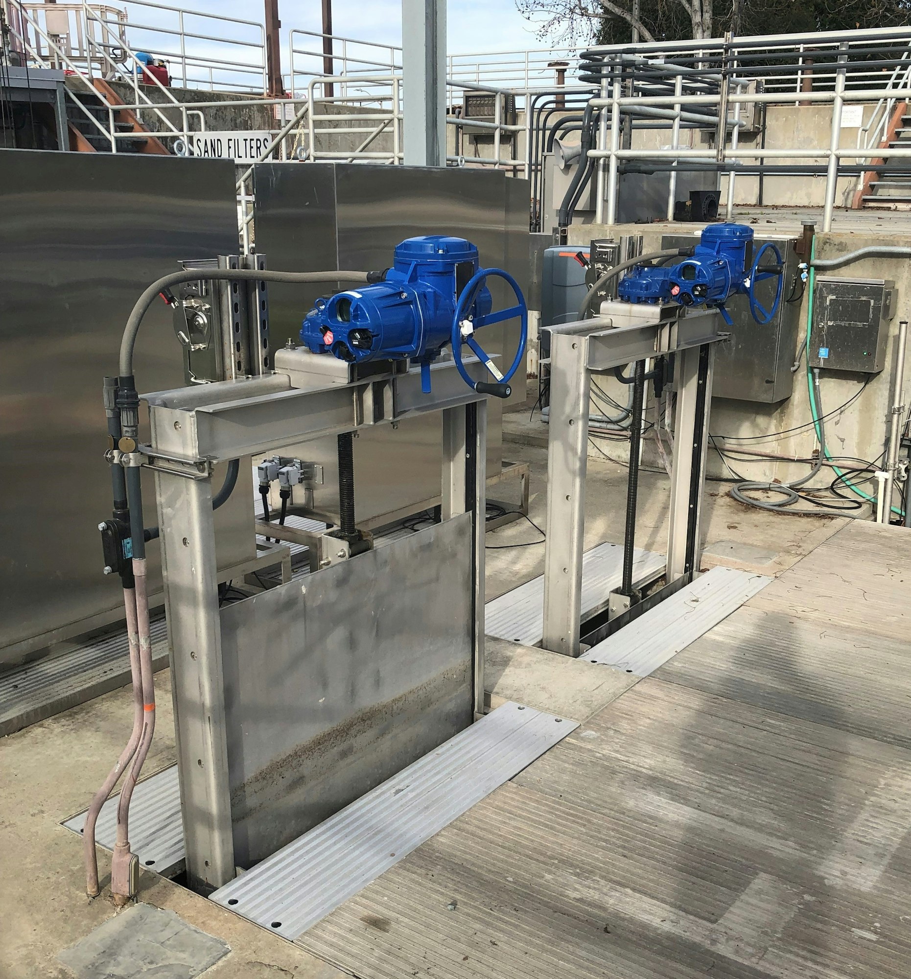 Metal gates with blue motorized controls at an industrial facility.