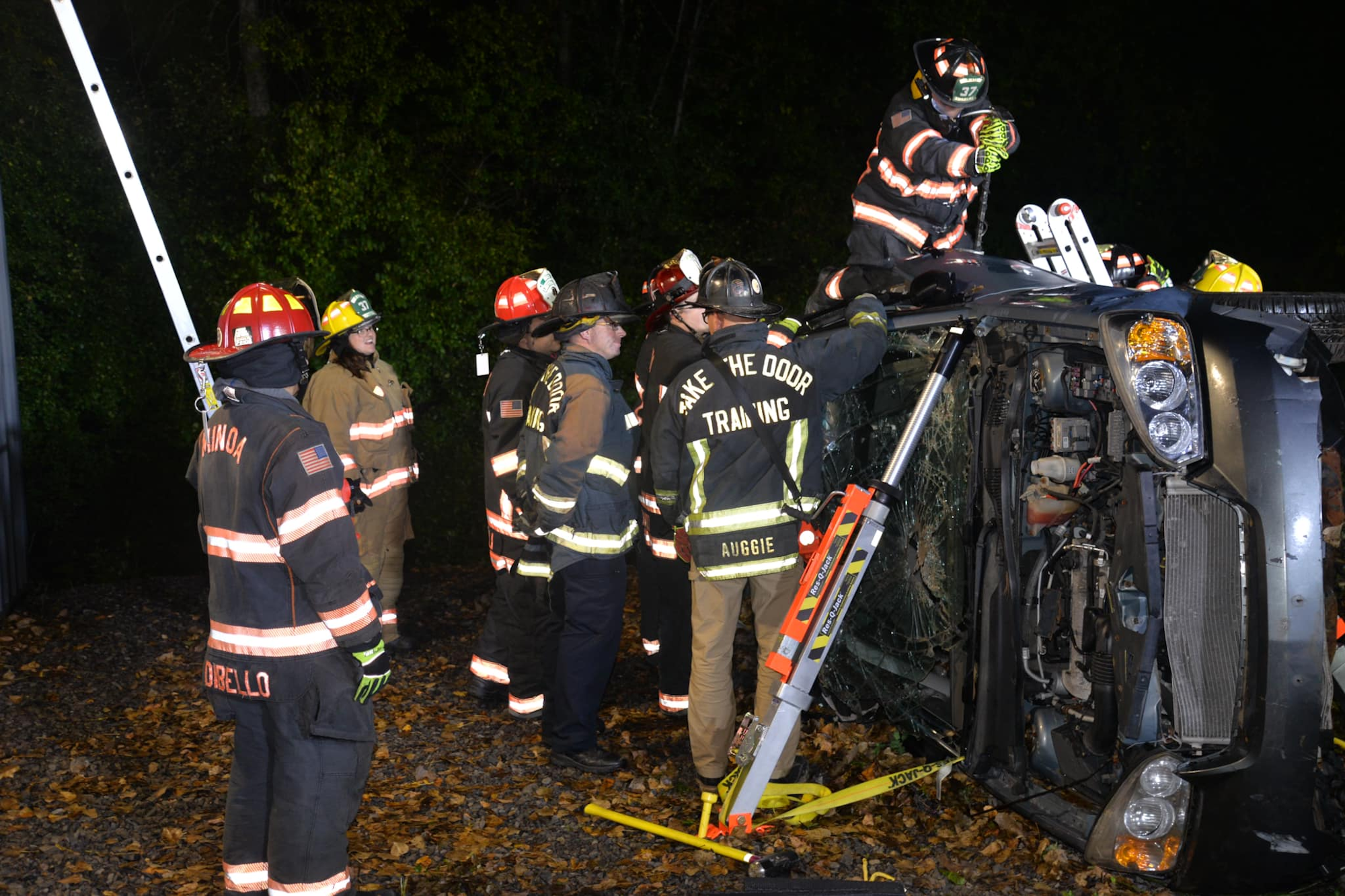 Firefighters at a vehicle rollover accident scene at night, with equipment for rescue operations.