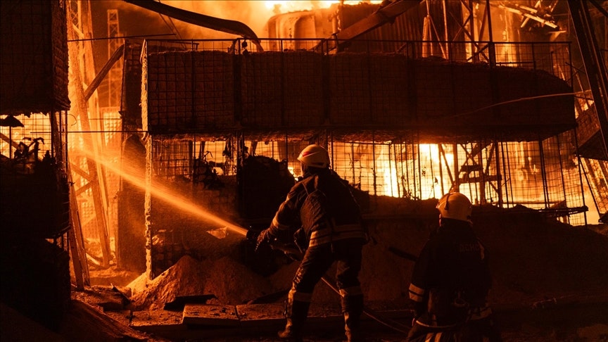 Firefighters battling a large blaze, spray water on flames engulfing a structure in a dramatic and intense scene.