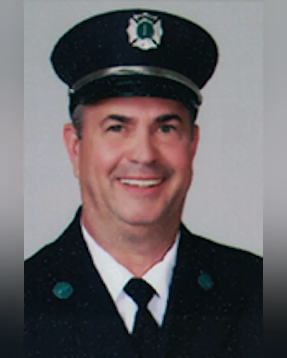 Ernie Greene wearing a formal uniform with a cap, smiling at the camera.