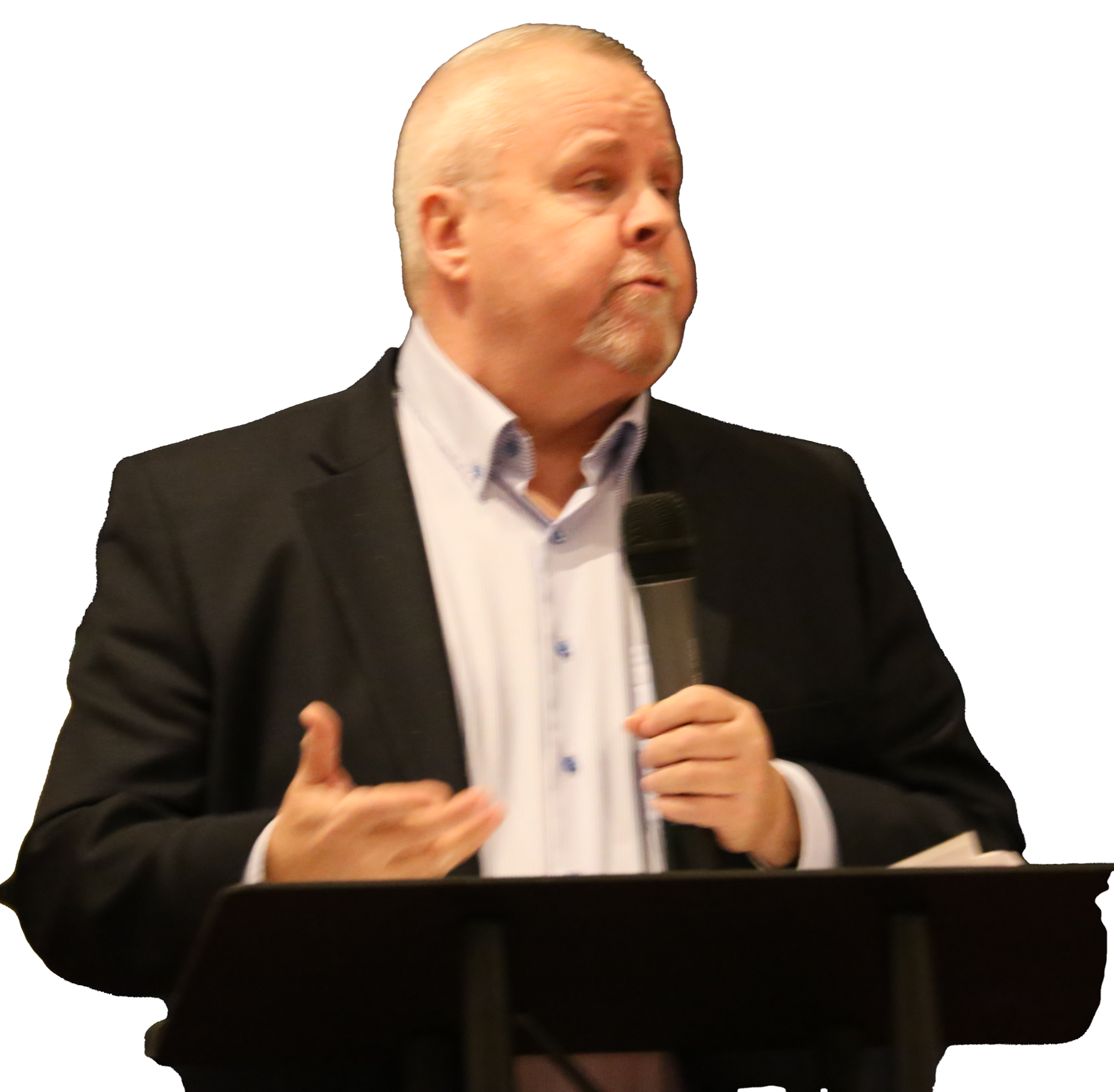Chuck Mullane in a suit speaking into a microphone at a podium.