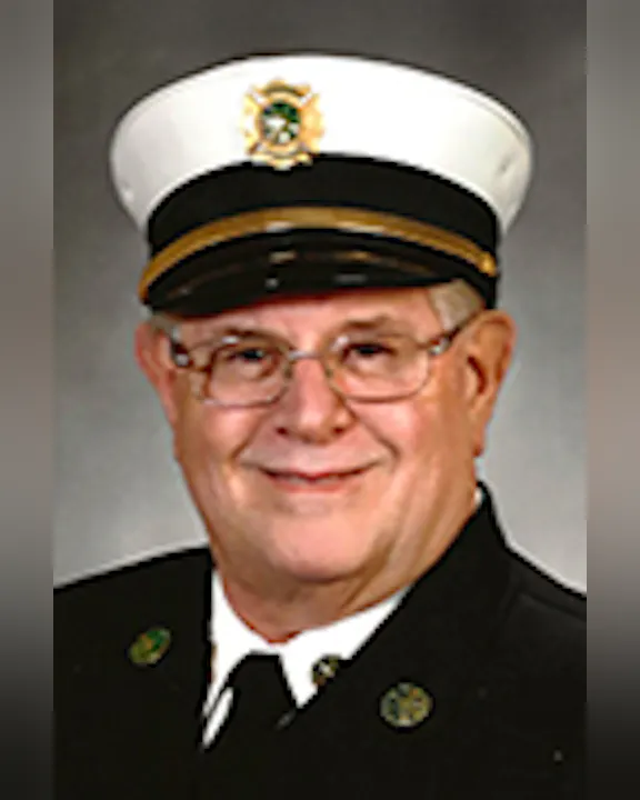 John, wearing a formal uniform with a white hat featuring a badge.