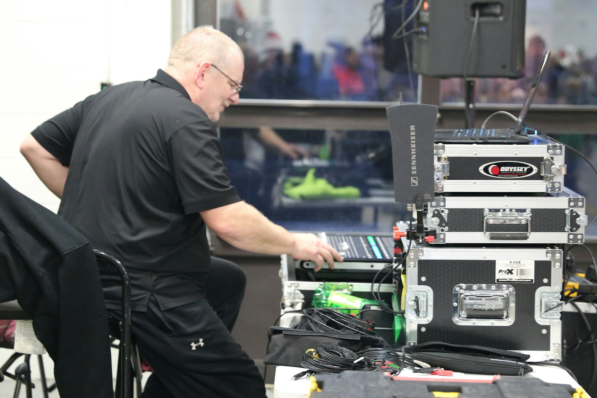 A person operating sound equipment with cases and cables.