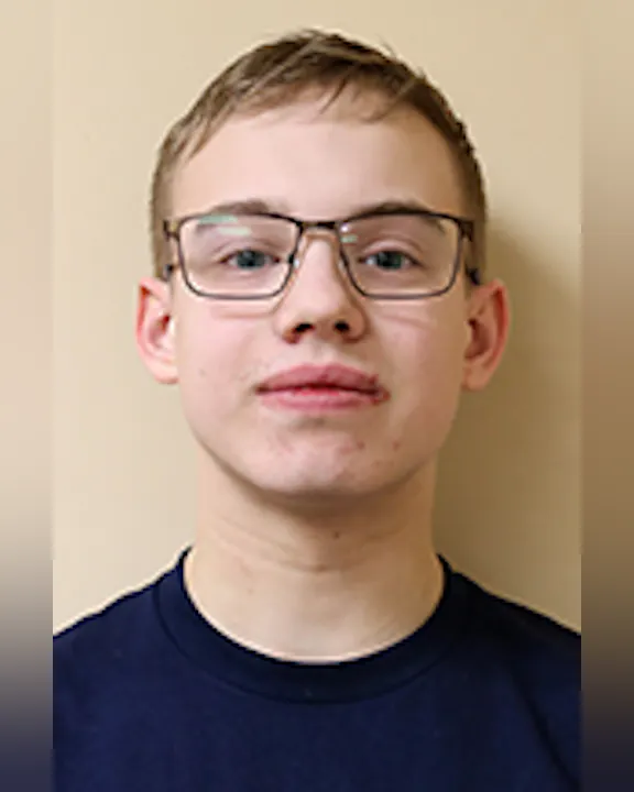 Connor Young wearing glasses and a dark shirt against a plain background.