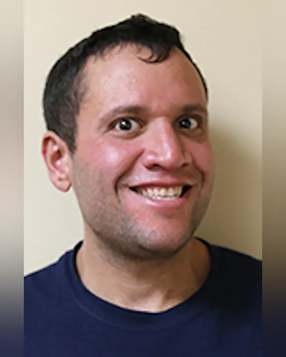 Randy Capriotti, Jr., smiling against a neutral background, wearing a dark shirt.