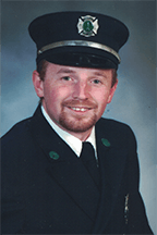 Erich Schepp in a firefighter's uniform, wearing a hat, against a neutral background.