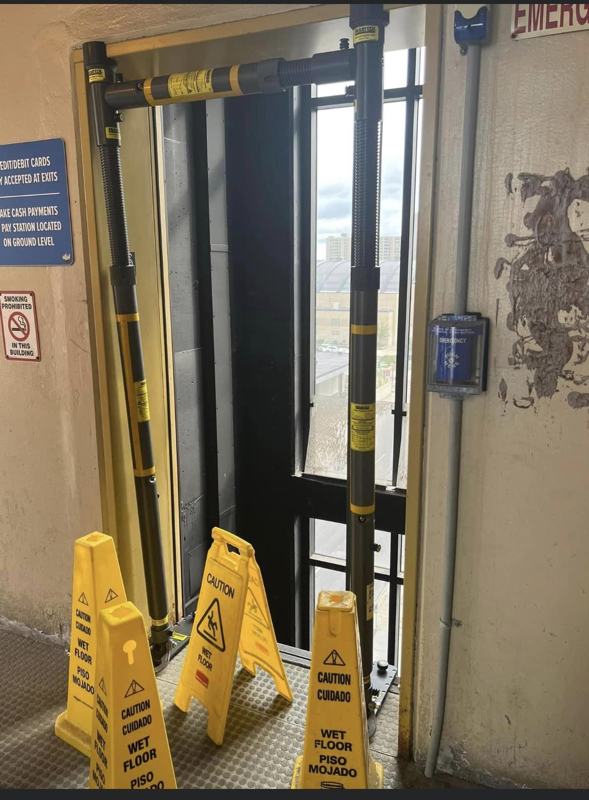 Elevator entrance barricaded with caution signs indicating a wet floor.