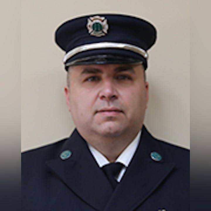 Nick Carulli in a dark uniform with cap and badge.