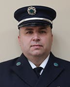 Nick Carulli in a dark uniform with cap and badge.