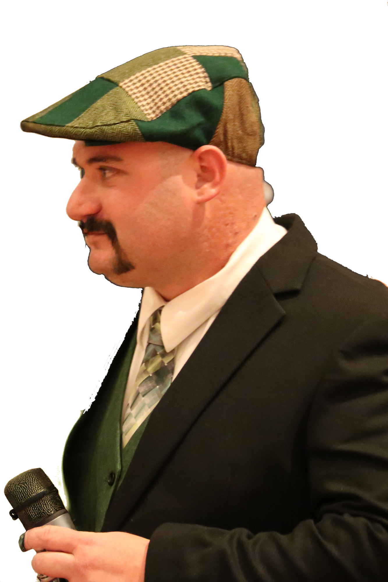Trevor Van Auken in a suit, holding a microphone, wearing a green and brown checkered cap.