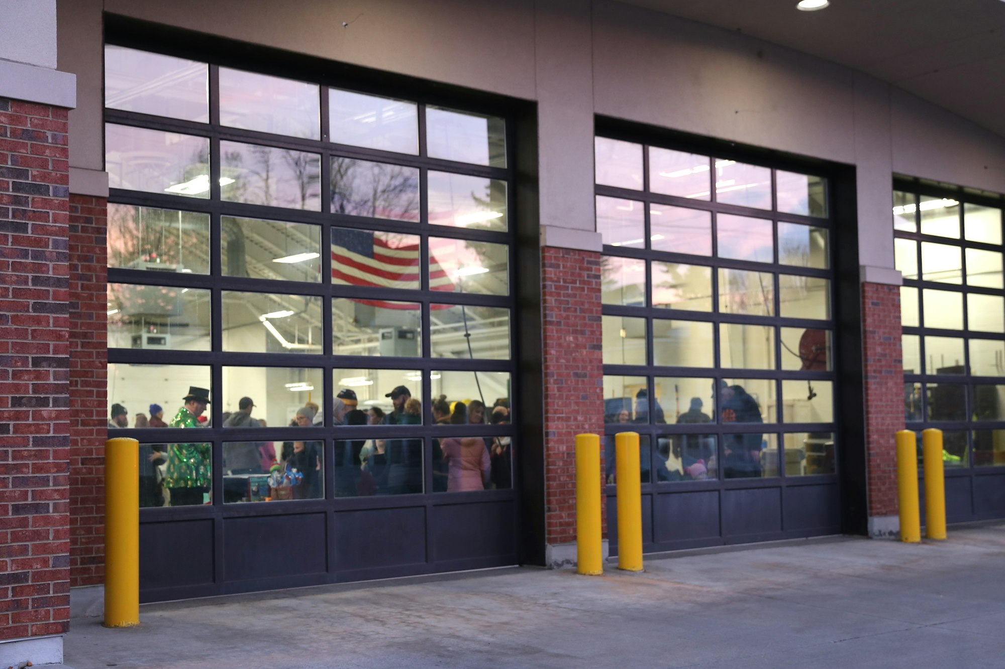 People gathered inside a building with large windows and an American flag visible.