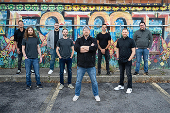 the bank Razberi Sumthing in front of a colorful graffitied wall.