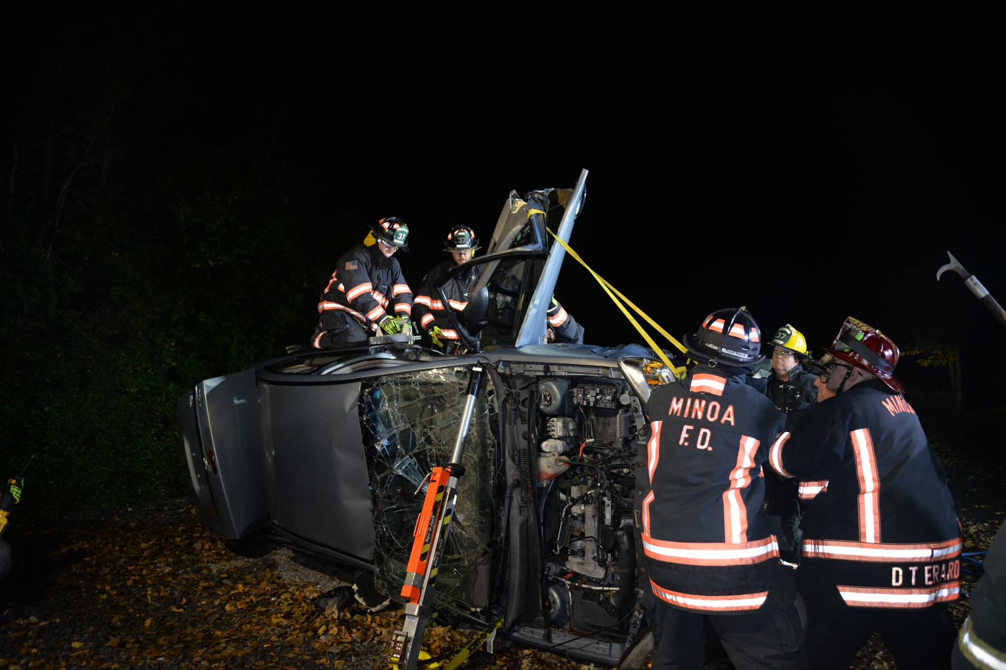 Firefighters at a night-time vehicle rescue operation.